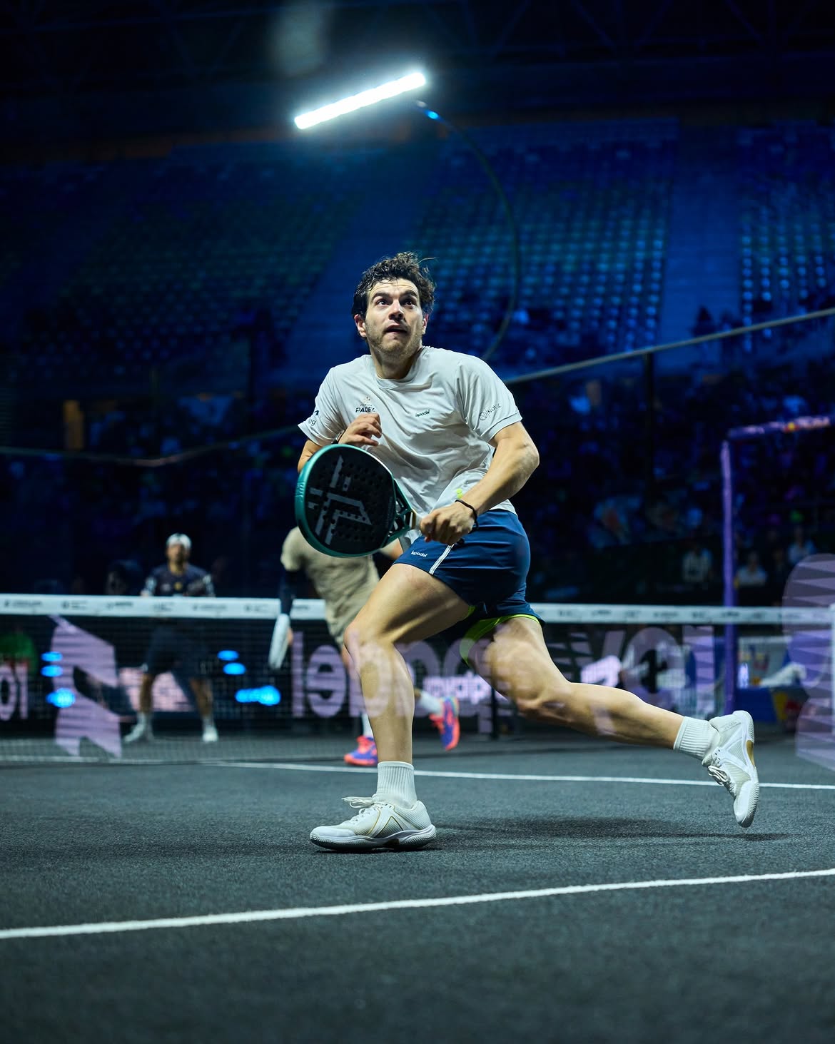 Professional padel player mid-action in a night arena